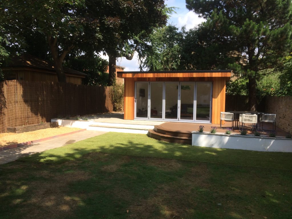 Grey sandstone patio and path with rendered walls, steps and planters and trex composite decking